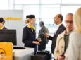 A passenger is communicating with a Lufthansa crew member at the gate, whilst holding his mobile device.