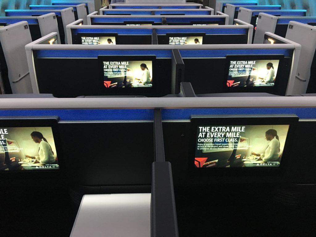 Delta One onboard the Delta 777, with large IFE screens in view