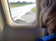 Young child looking out the window of an aircraft taking off.