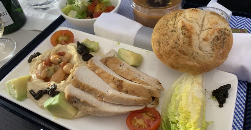 An airline meal tray with turkey and a roll