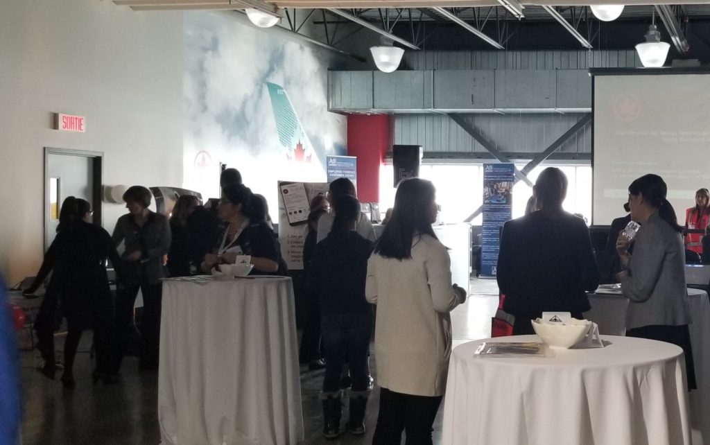 women standing up around tables listening to a presentation at Air Canada HQ