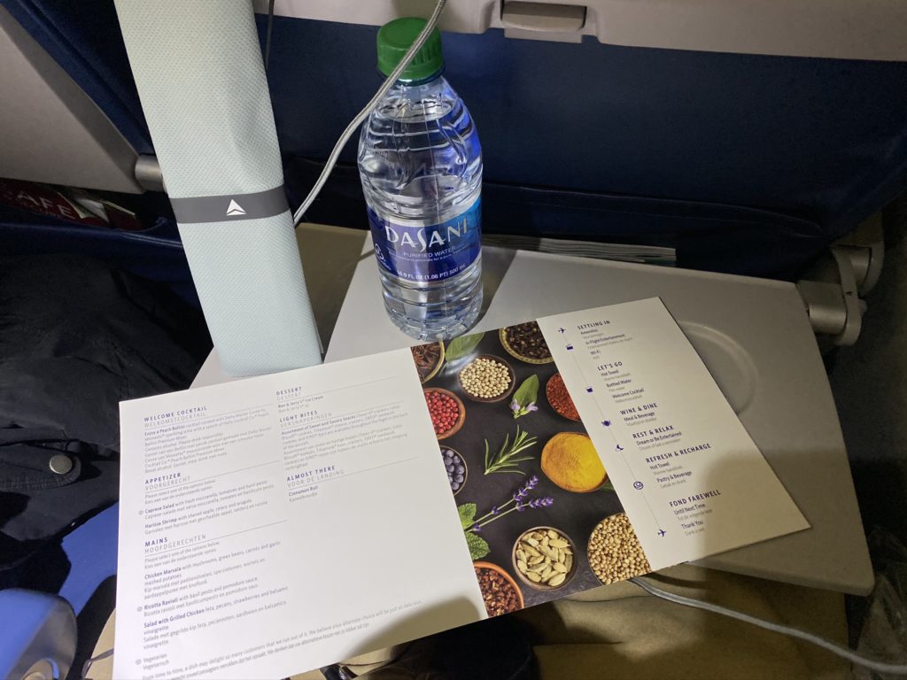 Menu, water bottle, and meal kit on aircraft tray table