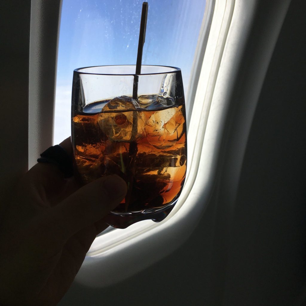 glass with drink and straw in front of aircraft window