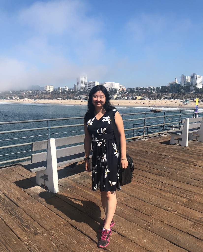 Tinglan Yang standing on a doc with the beach and water in the background