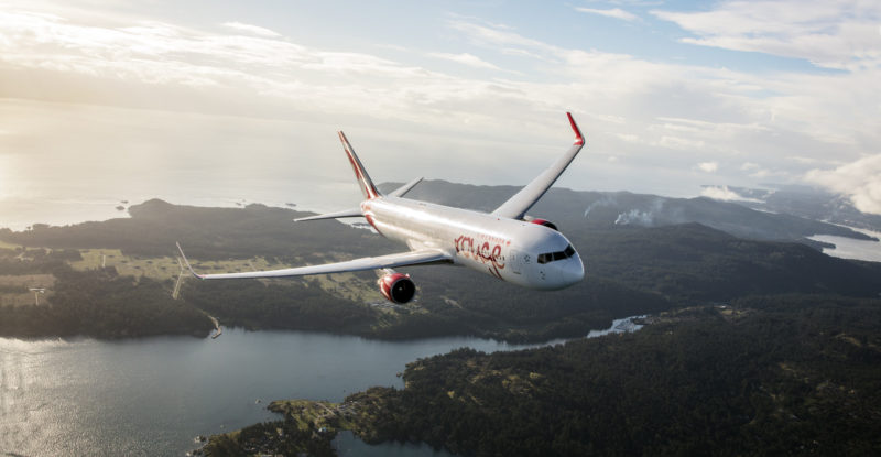 Air Canada Rouge aircraft flying over a scenic view