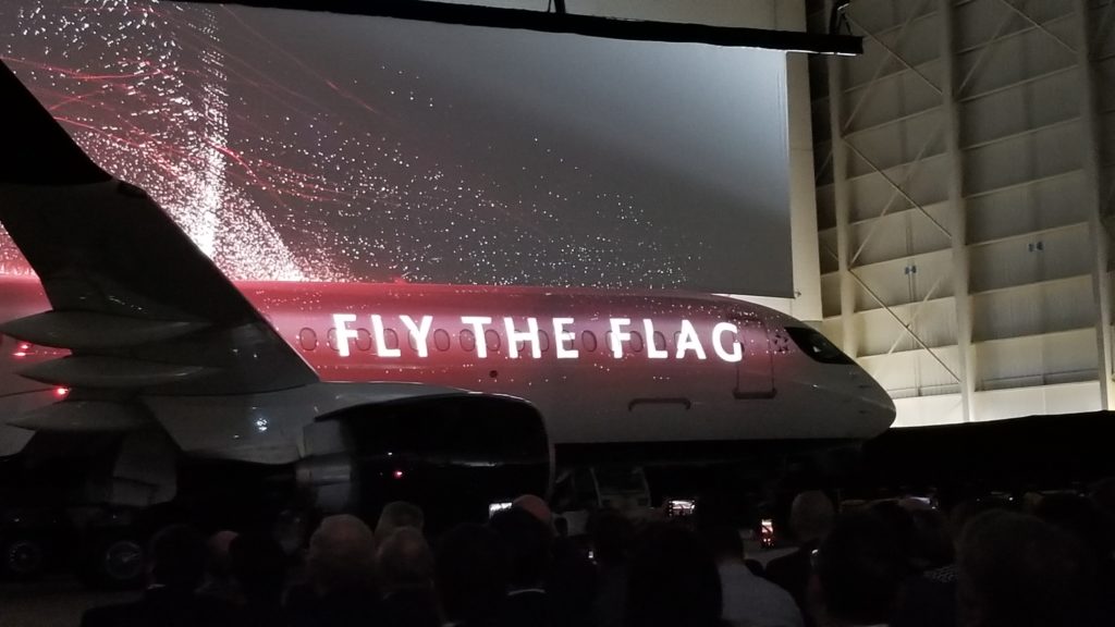 A photo of the A220 with the words "fly the flag" projected onto the side, as part of Air Canada's big reveal of the twinjet