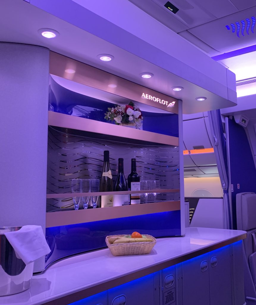 Business class bar in soft blue lighting stocked with different beverages and glasses