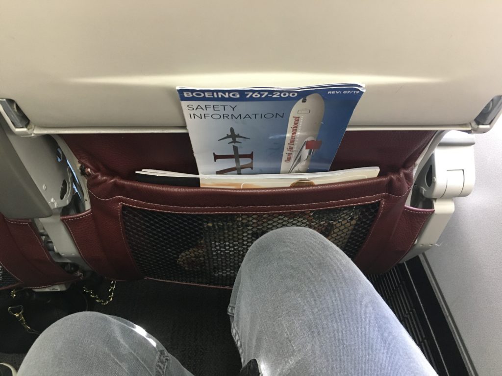 gentleman's knee bent showing the close proximity to the back to the seat in front of him when pamphlet's sit in the seatback pouch