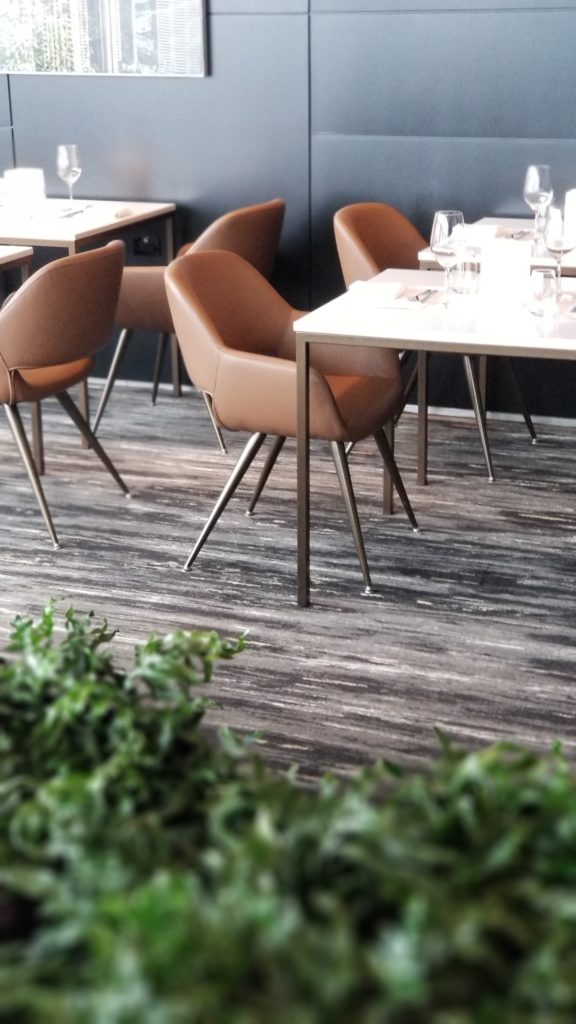 Tables for two set up with brown leather chairs looking over the tarmac of the airport