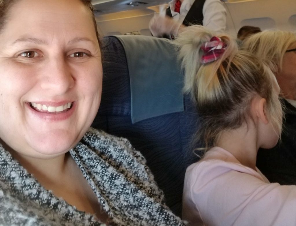 Woman posing for a selfie in her seat on the aircraft