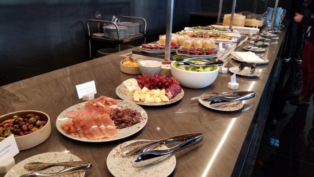 A buffet of different dishes, including meats, cheeses and salad on a wooden buffet table in the Signature Suite