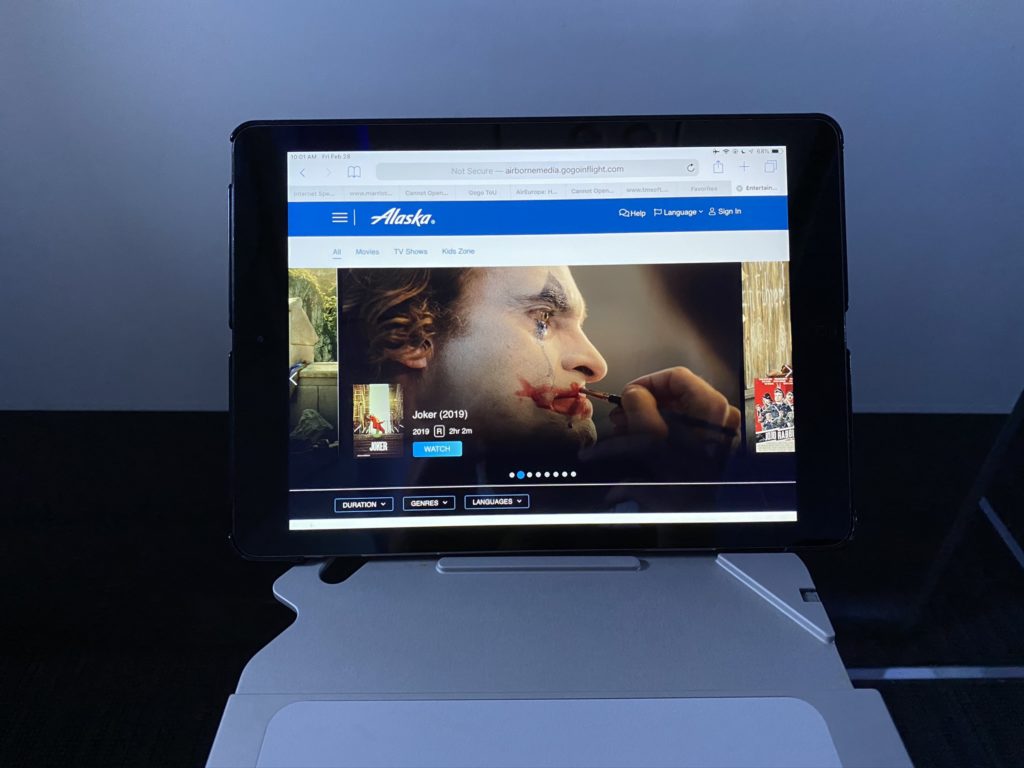 Tablet displayed in tray table tablet holder. Joker movie playing on the screen