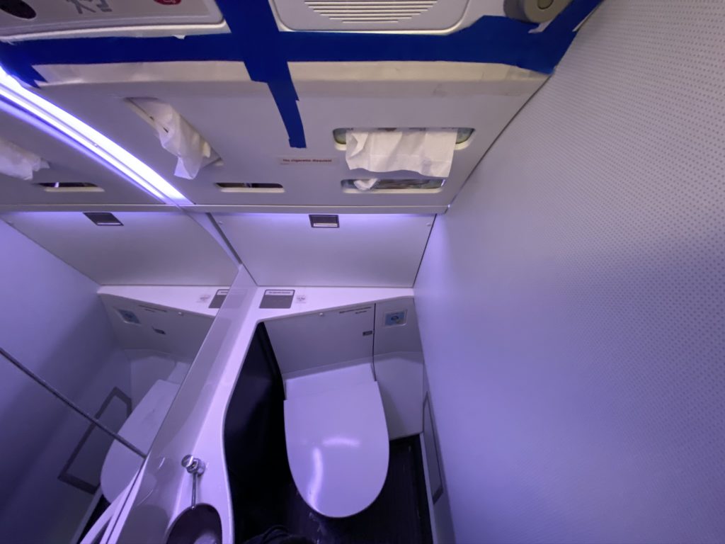 The tiny lav on the aircraft showing a view from the top over the toilet and tissue dispenser