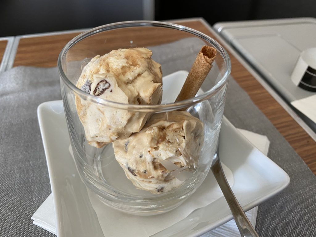 A clear bowl with two scoops of ice cream and a cookie stick