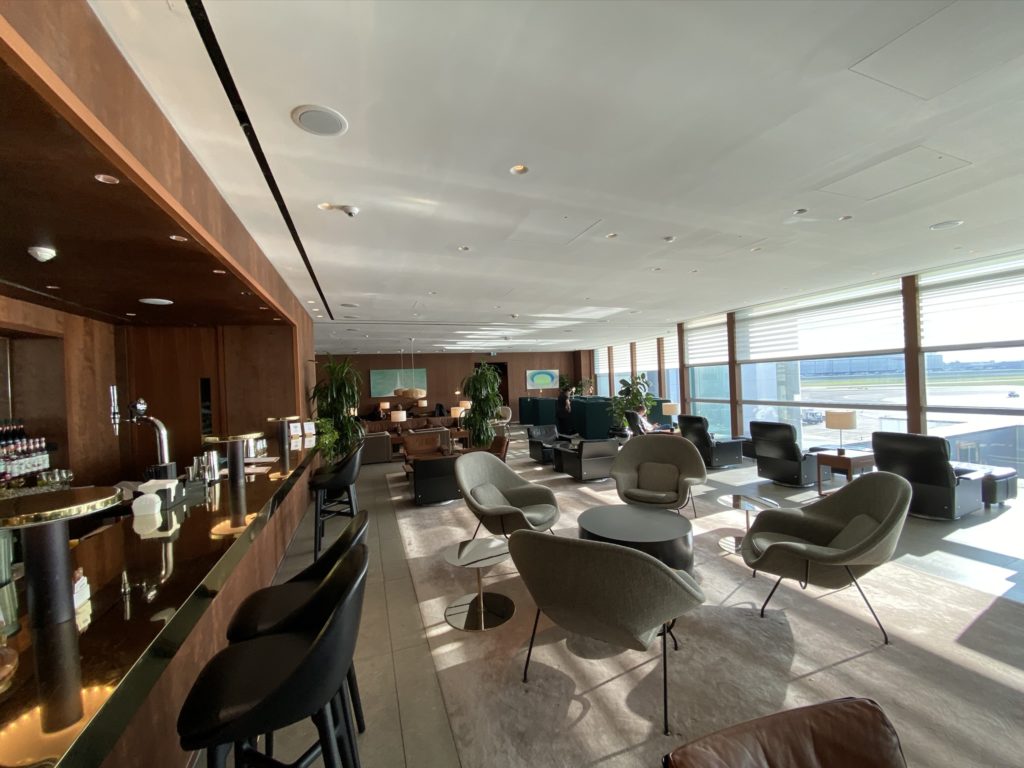 An empty lounge, including empty chairs and tables and an empty bar