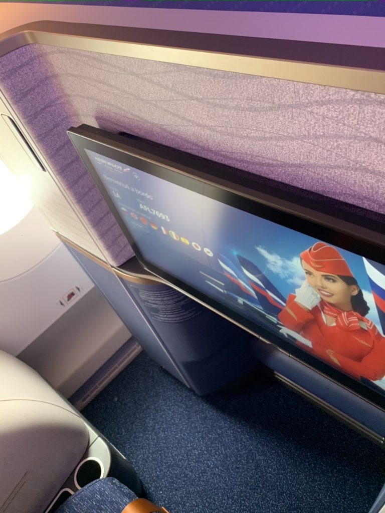 A photo of the Aeroflot Horizon suite with walls featuring a wave-like design and texture shrouding the large IFE screen