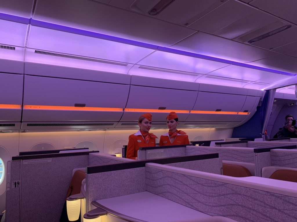 Purple and orange LED lights on the ceiling and overhead bins and two Aeroflot flight attendants in orange uniforms