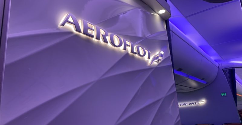 Bulkhead with white 3D brand element saying Aeroflot, with a purple LED-lit background with swirls