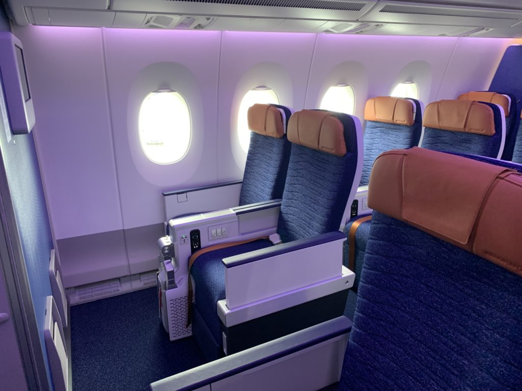 Aeroflot premium economy seats have both a luxurious and domestic fleet with blue seat covers and orange/bronze headrests. Seat rows are shown bathed in a pink/purple LED light