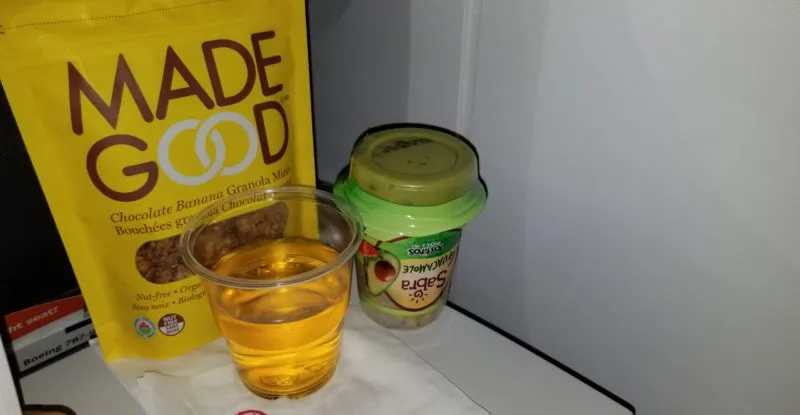 A bag of Made Good snacks on the aircraft tray table. Made Good is a top ten allergen-free food. It is often recognized for its allergen safety.