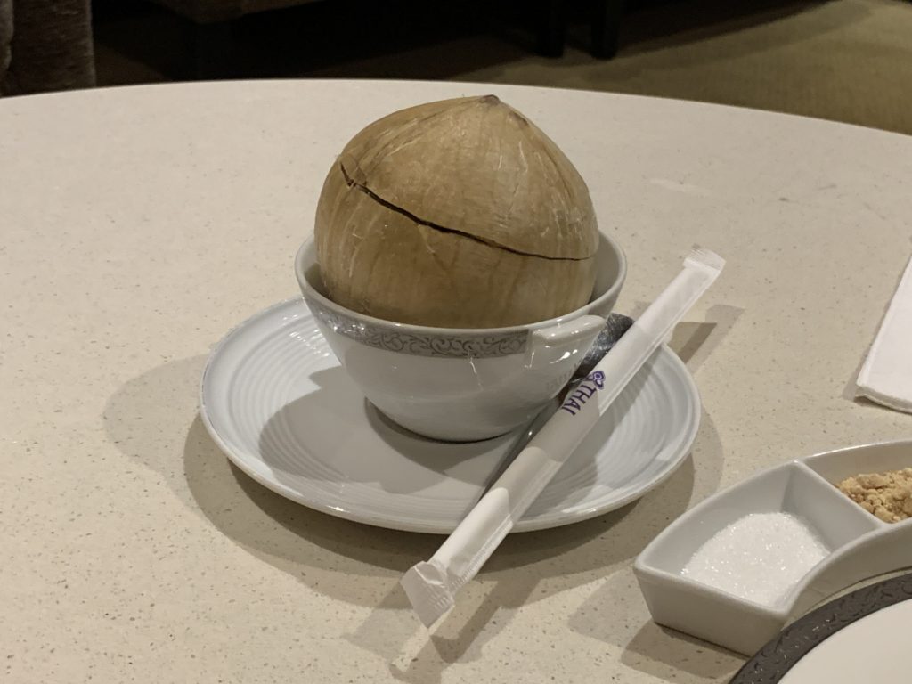 A coconut acts as a cup, and is presented in a ceramic bowl, with a straw