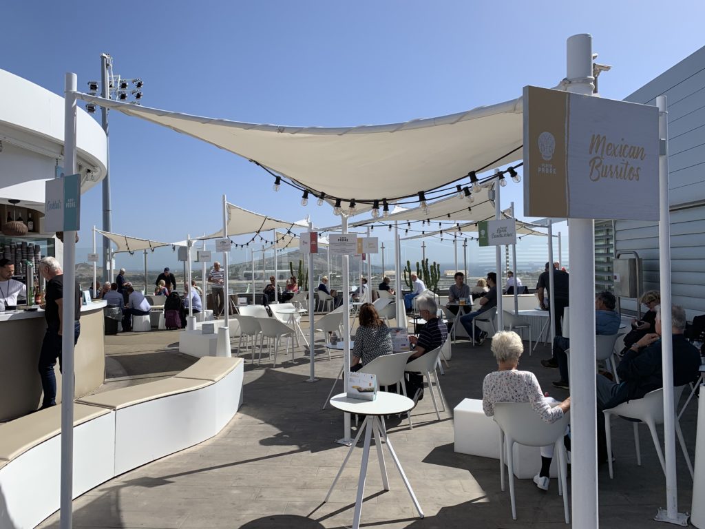 Gran Canaria's rooftop terrace bar with a bar, tables, chairs and canopies for shade. People are shown relaxing, enjoying the shunshine while seated