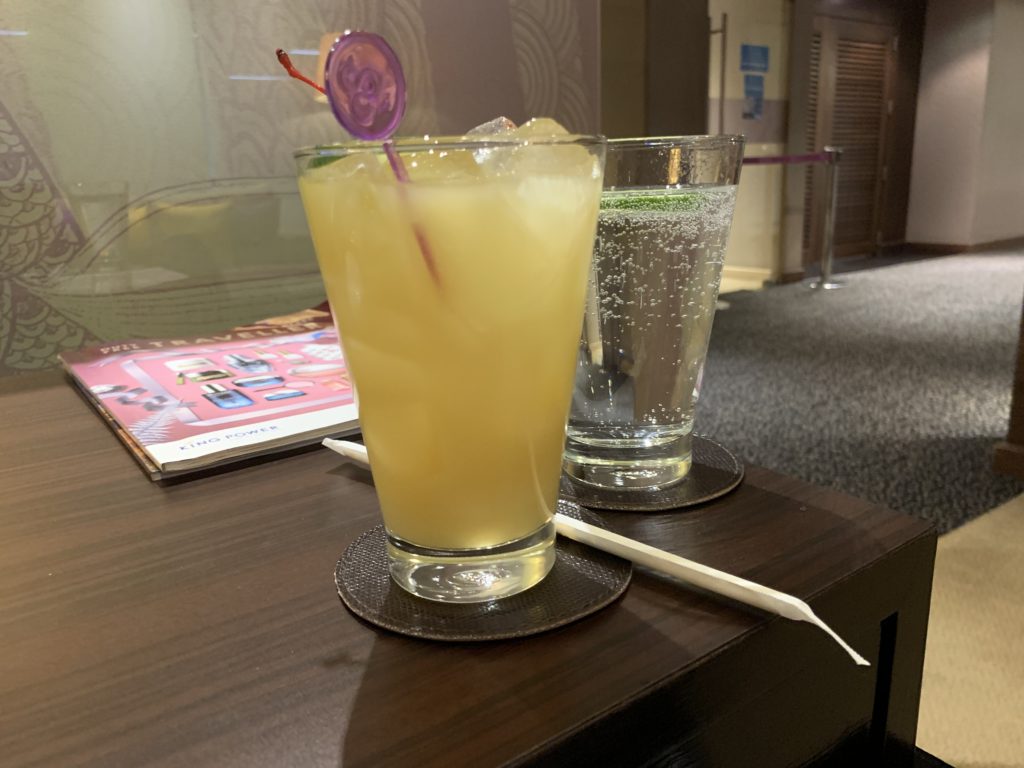 A yellow virgin piña colada in a glass with a purple plastic mixing straw