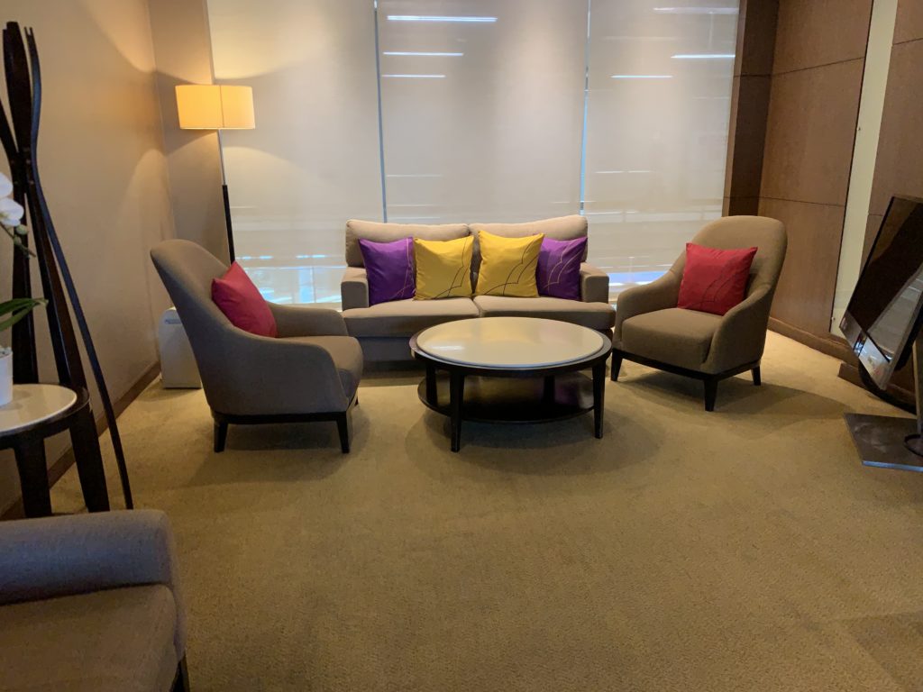 Two chairs and a love seat with multi-covered pillows in a semi-open space with a coffee table