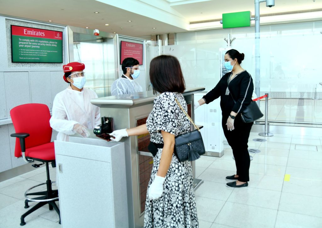 Emirates frontline employees, wearing face masks, check in passengers at the airport