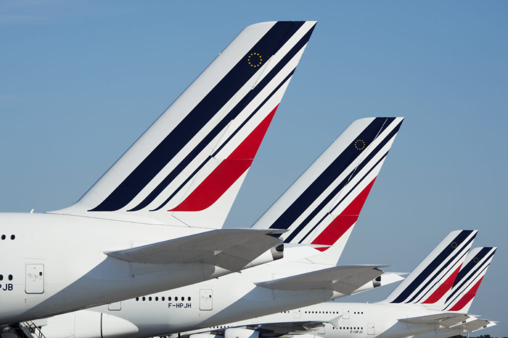 A series of parked A380 tails; the Air France colors are on display with a blue sky in the background