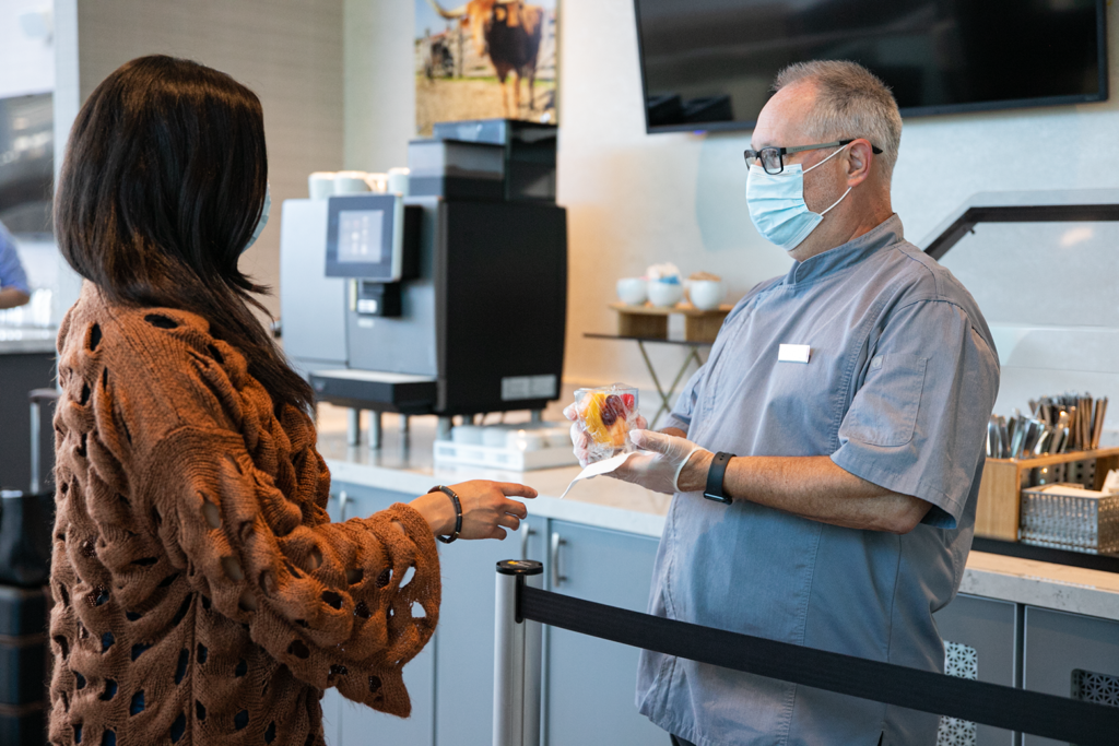 A female passenger receives a prepared snack from a Sodexo employee, rather than access the buffet 