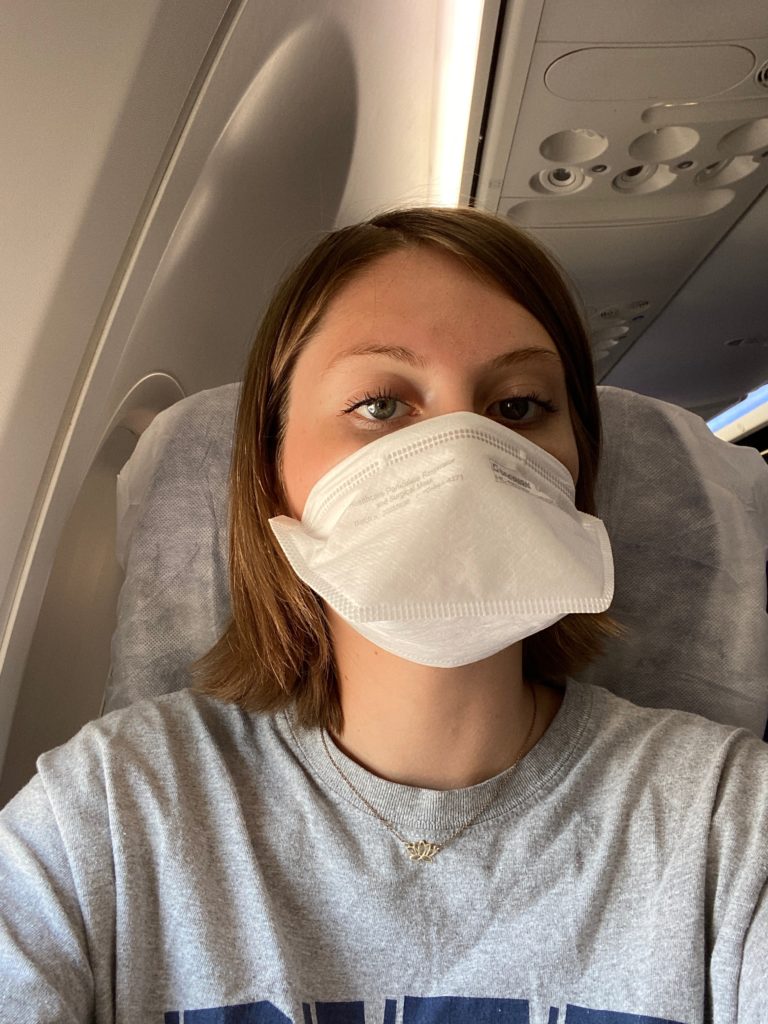 A photo of the author on board the Southwest 737. She is wearing a mask, and sitting on a seat cover from Seat Cuvers 