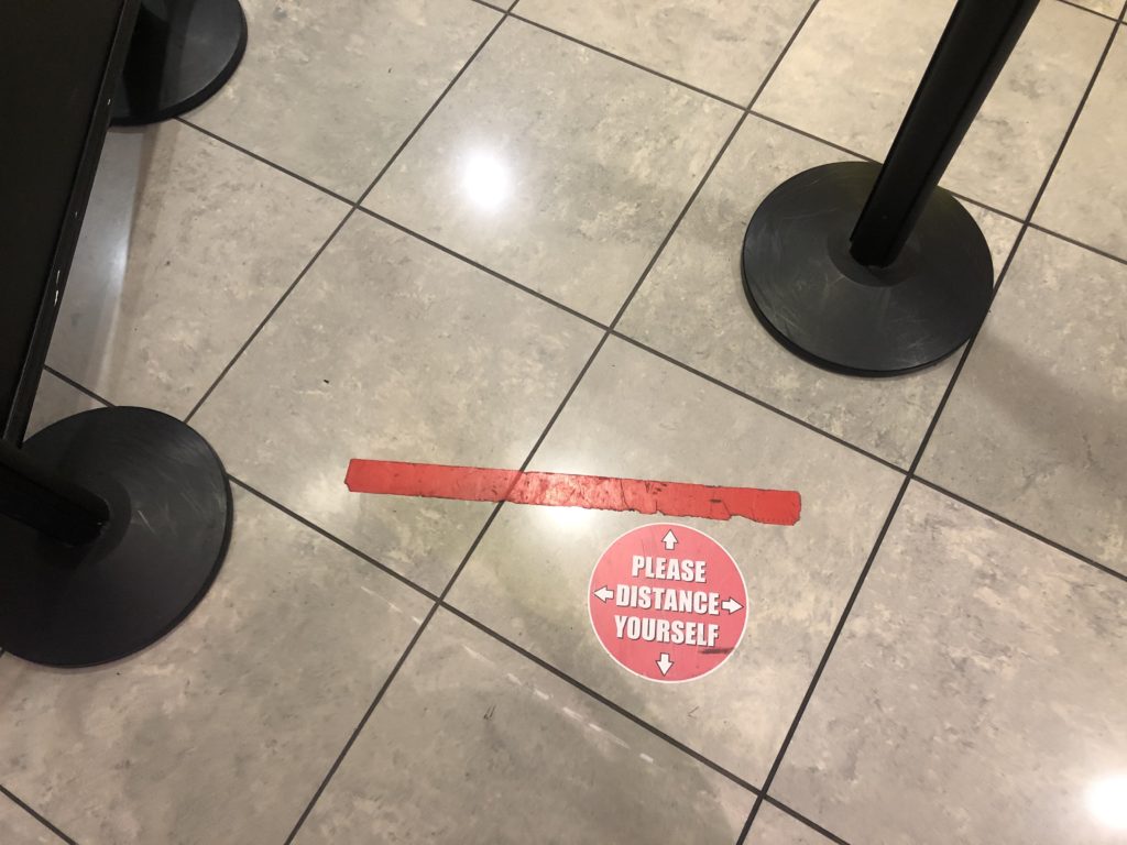 A sticker on the ground at security, saying: "Please distance yourself"