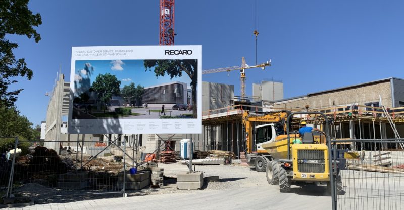 A large billboard with the name Recaro on it, and a blue sky as backdrop