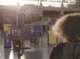 A person with curly hair standing in front of the thermal imaging camera kiosk