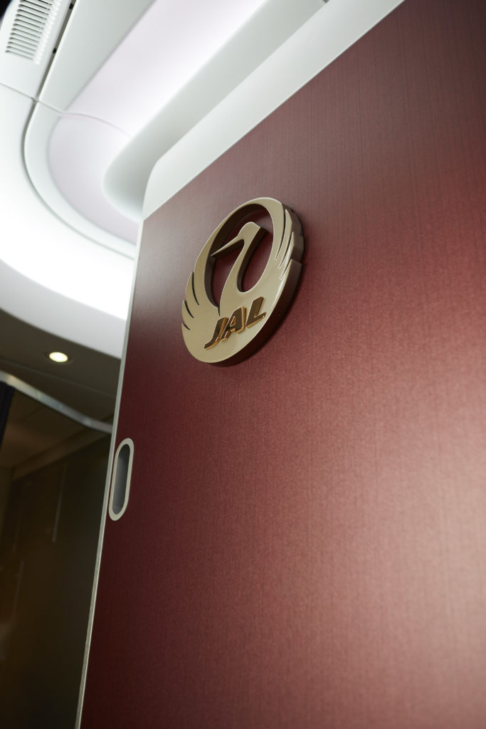 The gold JAL cabin crest on a monument in the aircraft cabin