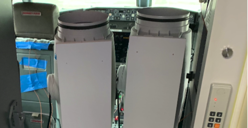 Two tall grey thermal sanatizes in the cockpit of a Boeing aircraft