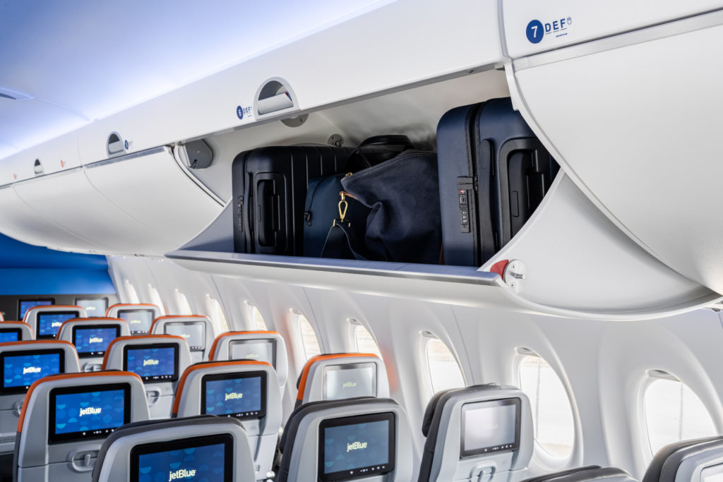 JetBlue A220 overhead luggage container is open with carryon stowed inside