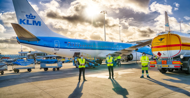 A KLM 737 in the carrier's signature blue livery sits beside a yellow Shell truck at the gate. A glorious sky is in the background, with clouds and sun streaming through (government)