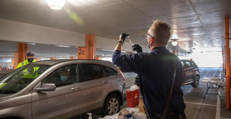 A woman readies to give the COVID-19 vaccine to occupants of a car at SFO Airport