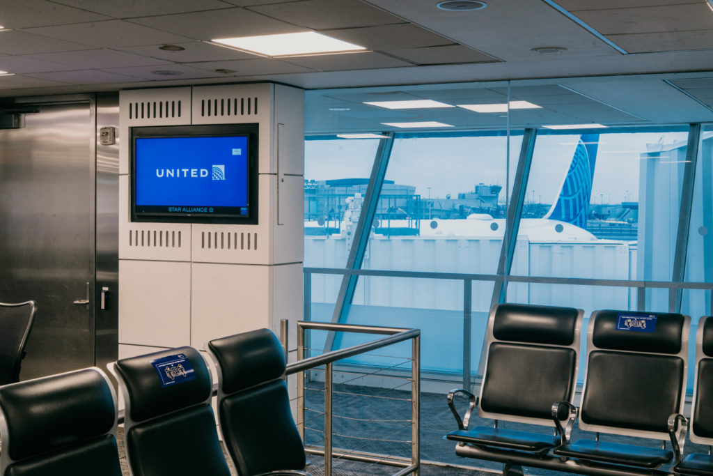 United Airlines gate showing seating, United on the information screen and an aircraft out the window.