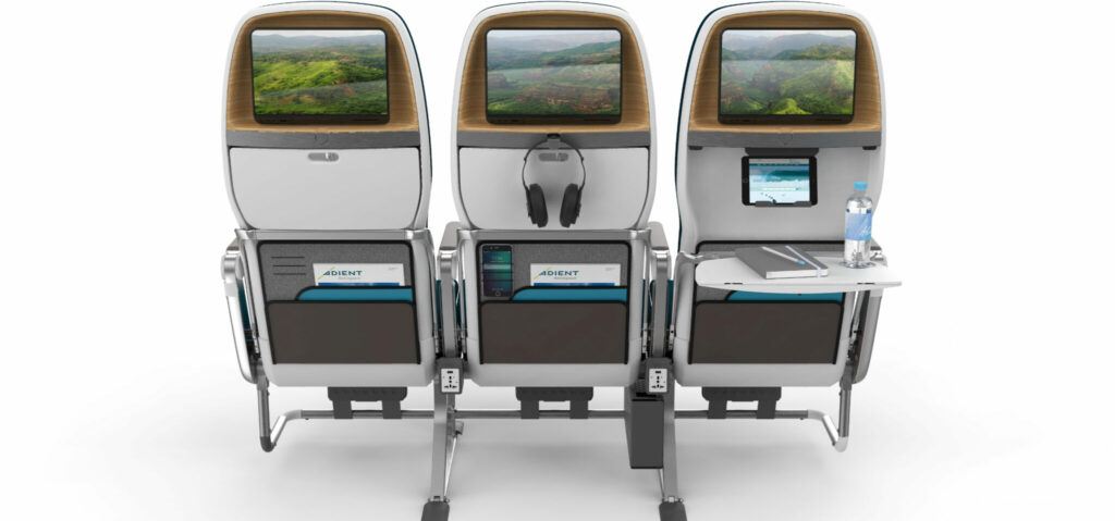 Adient Aerospace's Ovation seat in A Boeing 787 model. Showing the back with tray table, headphone holders, tablet holder, IFE Screen and other additions.