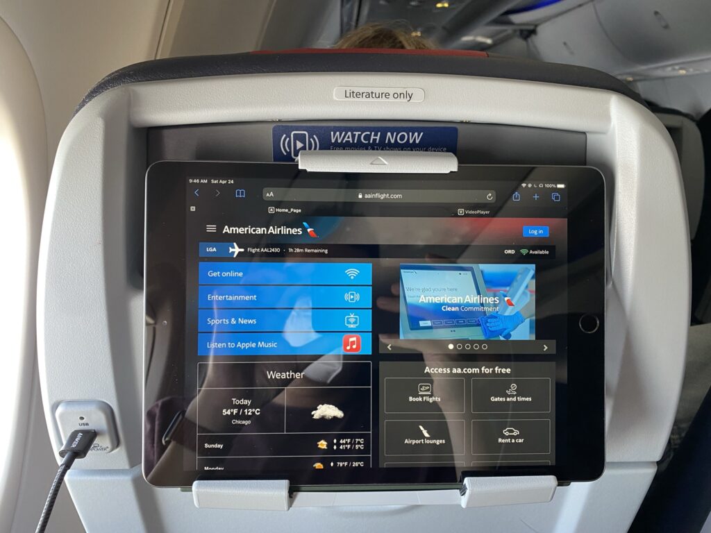 PED holder on the back of an economy class seat being used. Device is showing the IFE selection on board American Airlines.