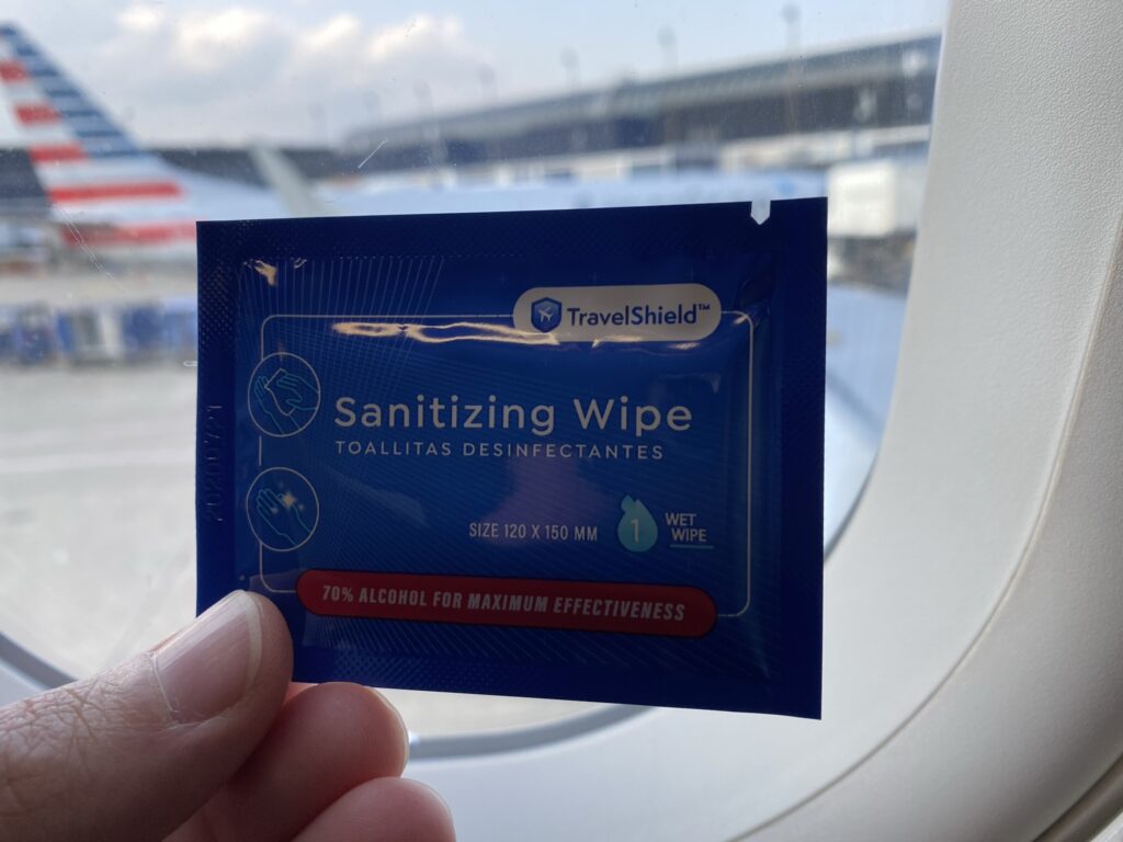 American Airlines sanitizing wipe held up in front of an aircraft window.