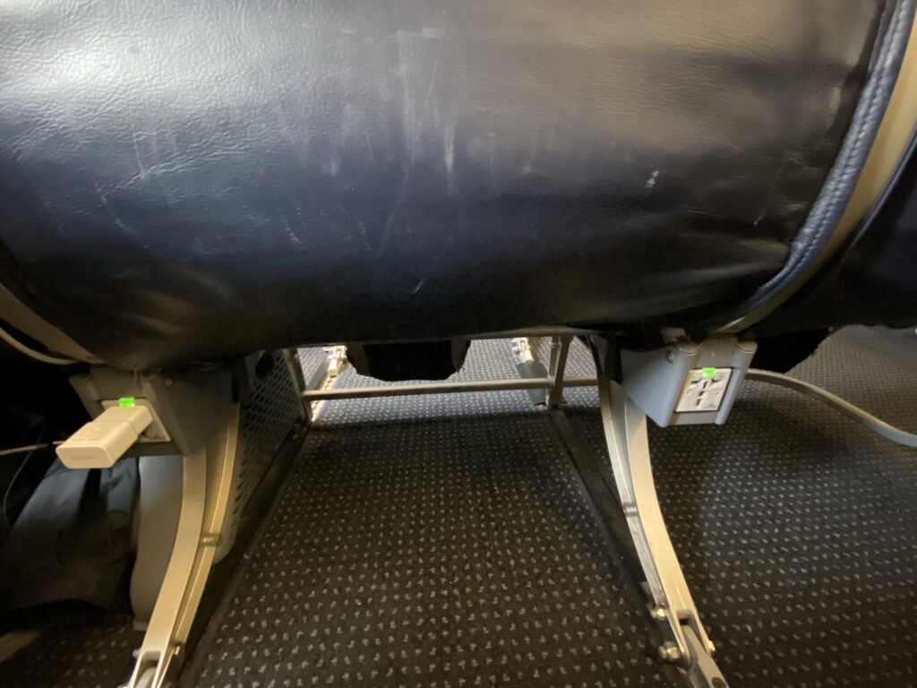 Bottom of the aircraft seat on American Airlines A319 show power outlets.