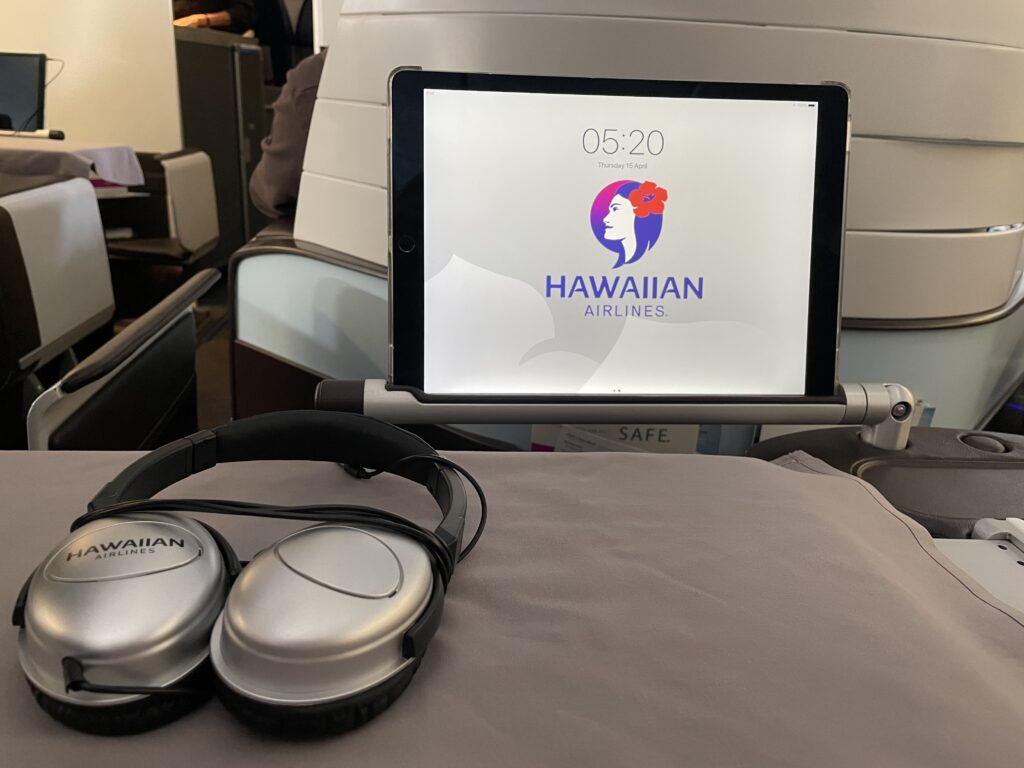 Hawaiian Airlines Ipad on a holder. The holder is a bar that pulls out from the seat.