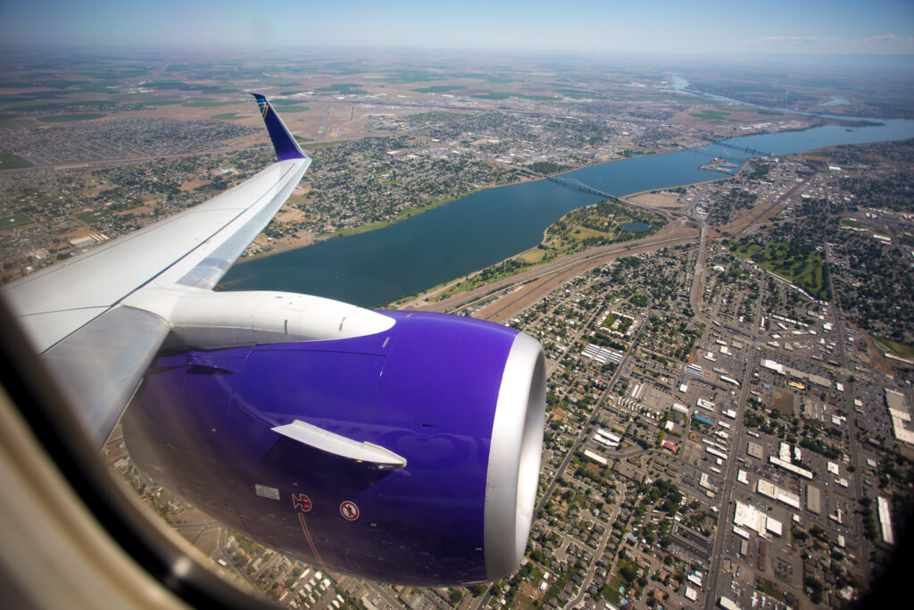 View out the window for an aircraft inflight. You can see the purple livery on the engine. 