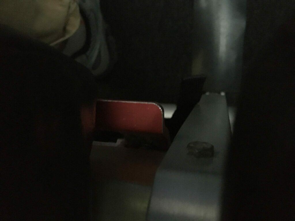 Red handle hidden down in the side of an aircraft seat that is used to recline