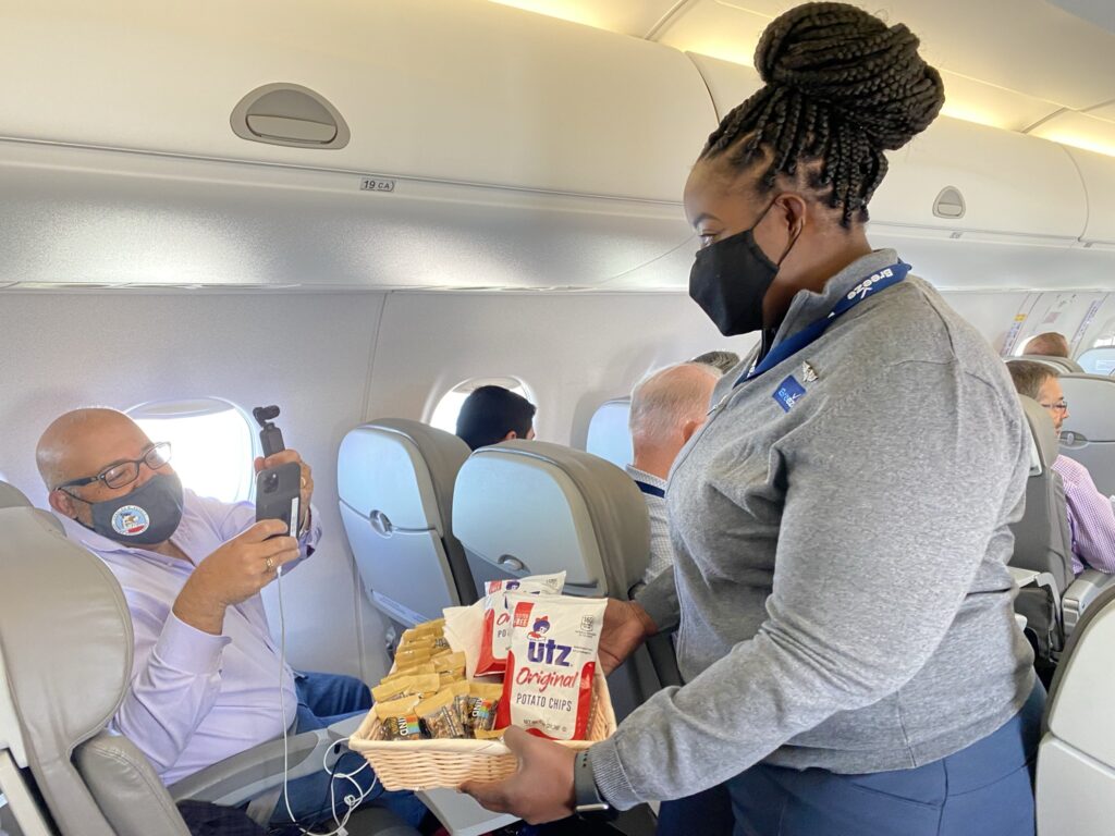 A female flight crew hands UTZ snacks to an aviation enthusiast aboard the flight