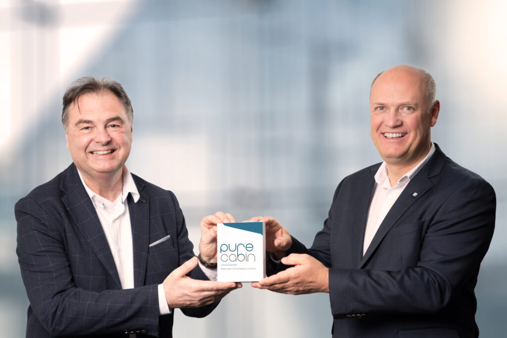 Two men standing side by side holding a Pure Cabin box.